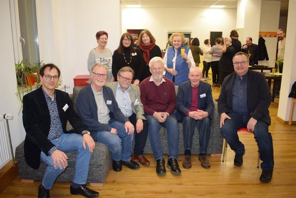 Das Bild zeigt eine Gruppe von Personen, die auf einem Sofa sitzen.