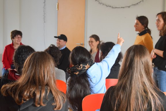 ejsa Regensburg / Valentum Kommunikation GmbH (Teresa Hofmann) Das Bild zeigt ein Kind, das sich meldet von hinten. Im Hintergrund sind mehrere Personen zu sehen.