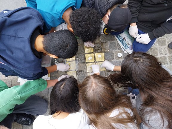Dr. Simone Aicher-Frank Draufsicht auf Kinder, die Stolpersteine putzen.